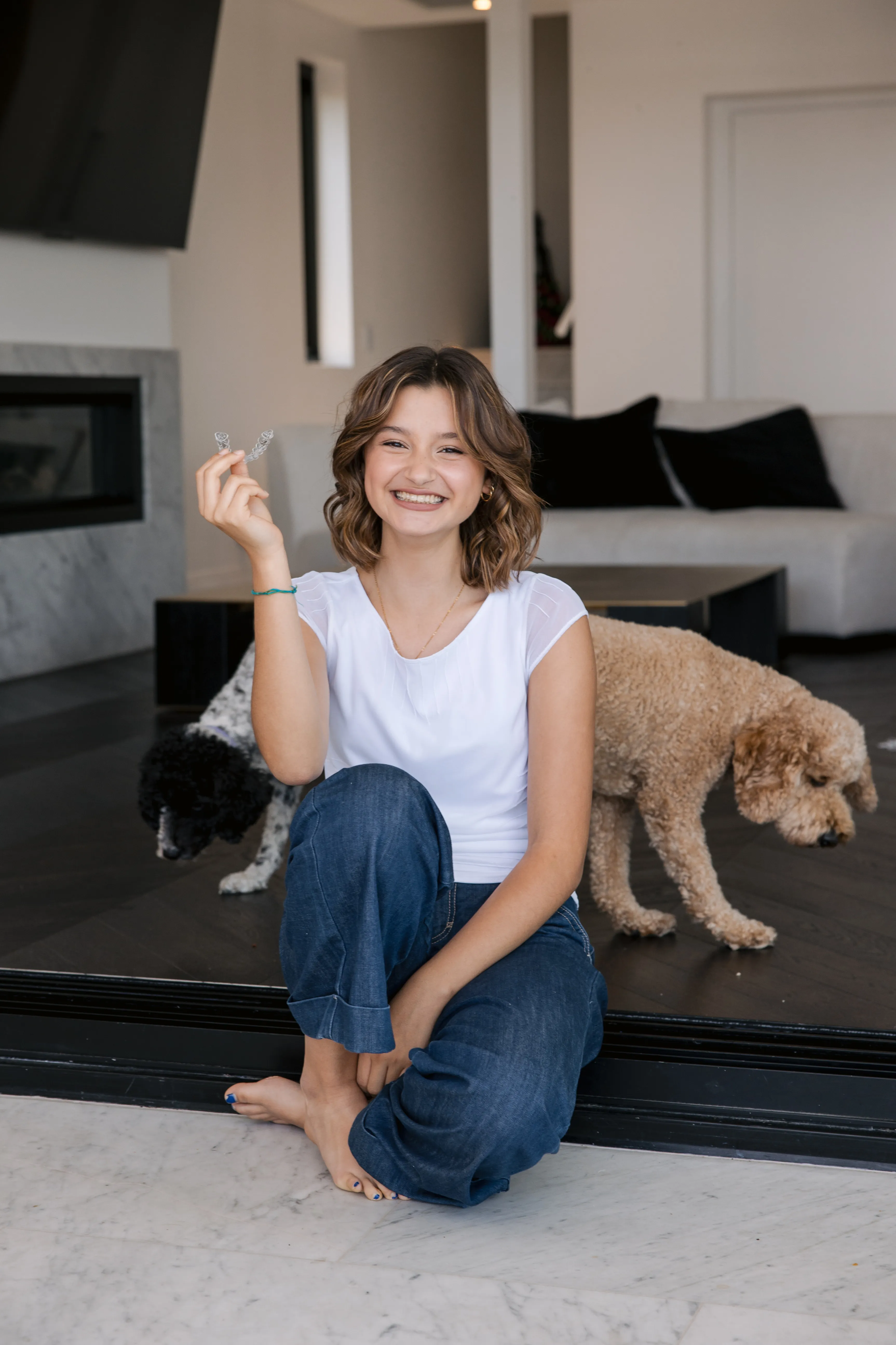 Teenage patient holding clear Invisalign aligner at home