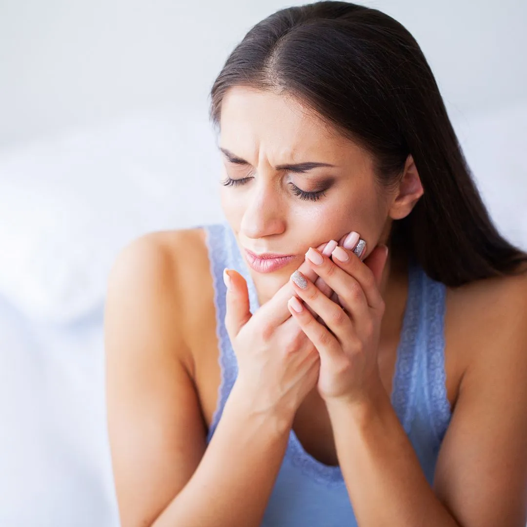 Person holding their jaw with severe toothache before an emergency dental appointment